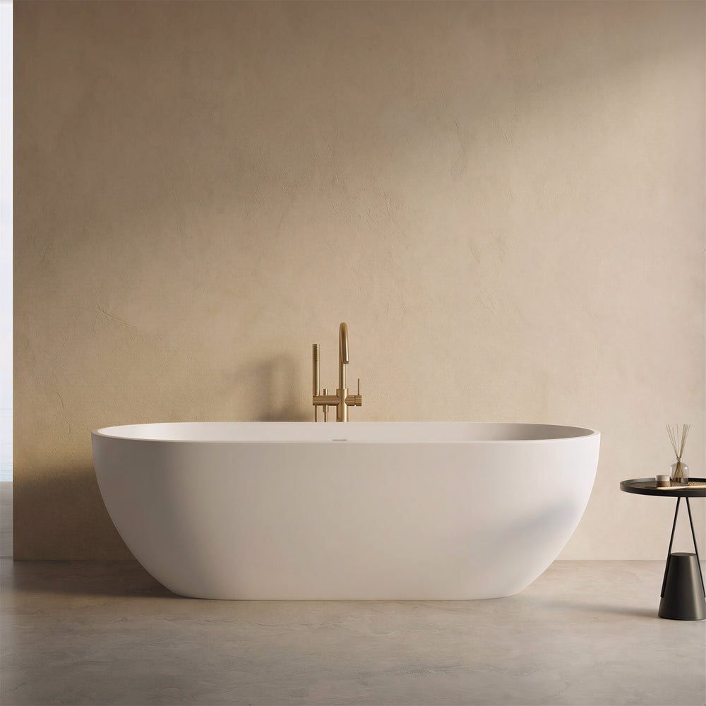 AURELLE 69-inch minimalist oval freestanding solid surface bathtub with brushed gold faucet in a beige bathroom